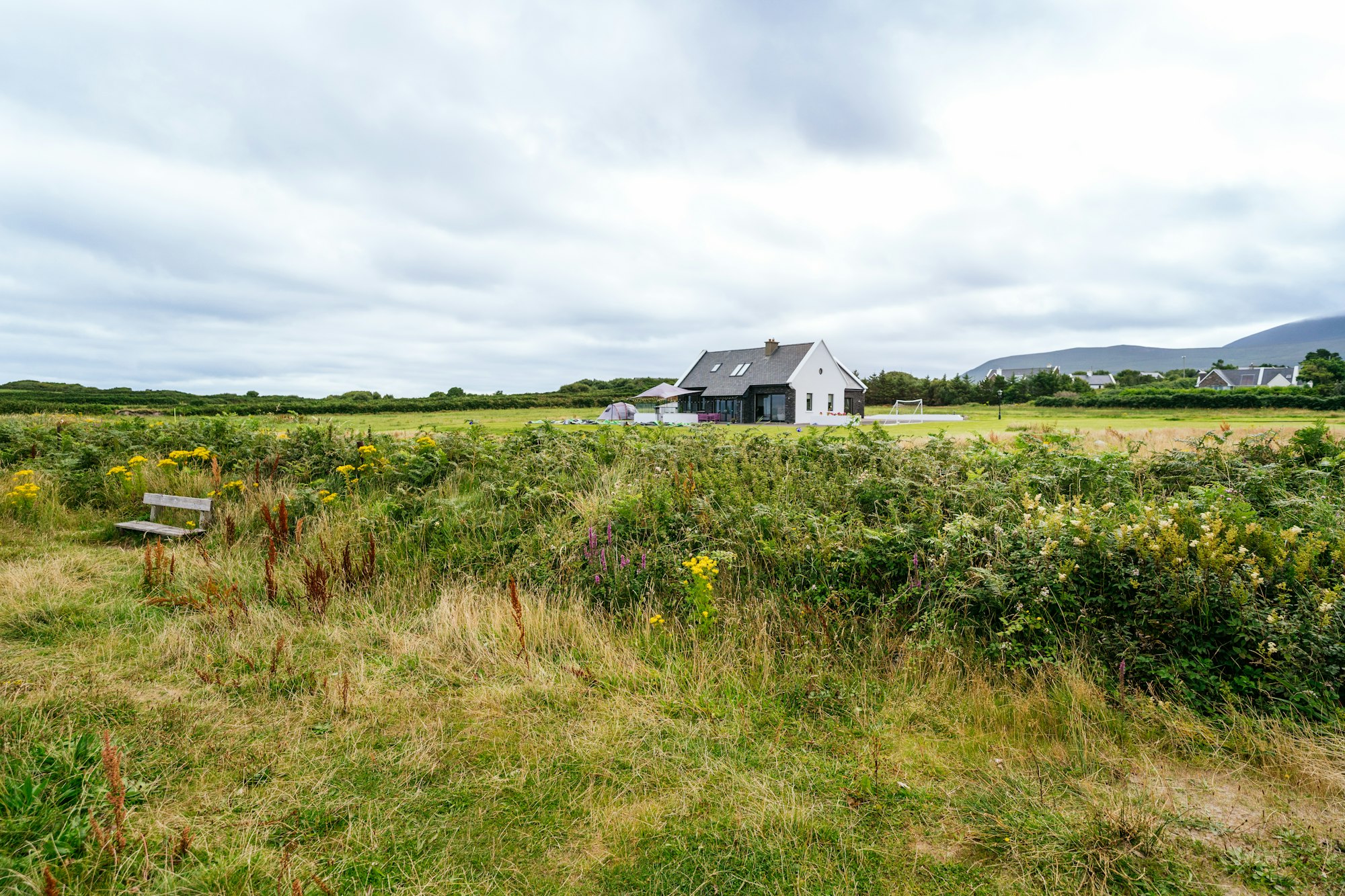 Enchanting Irish Landscape: Serene House Amidst Green Meadow, Towering Mountains